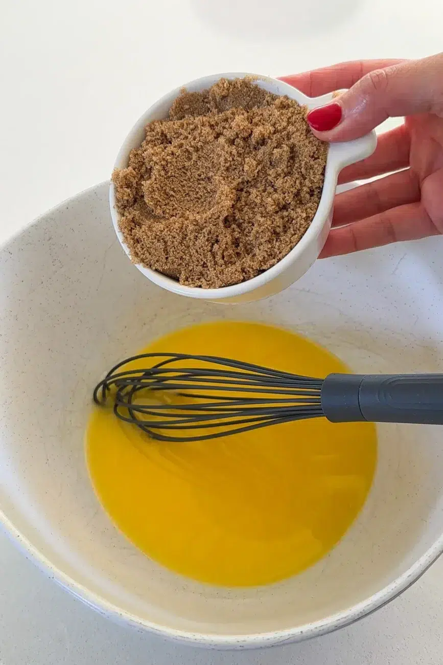 Brown sugar being added to melted butter for whisking