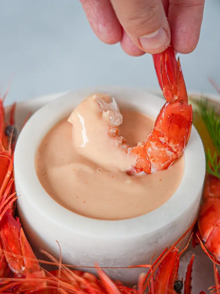 Close-up of a prawn dipped in Cocktail Sauce, showcasing its creamy texture and fresh ingredients