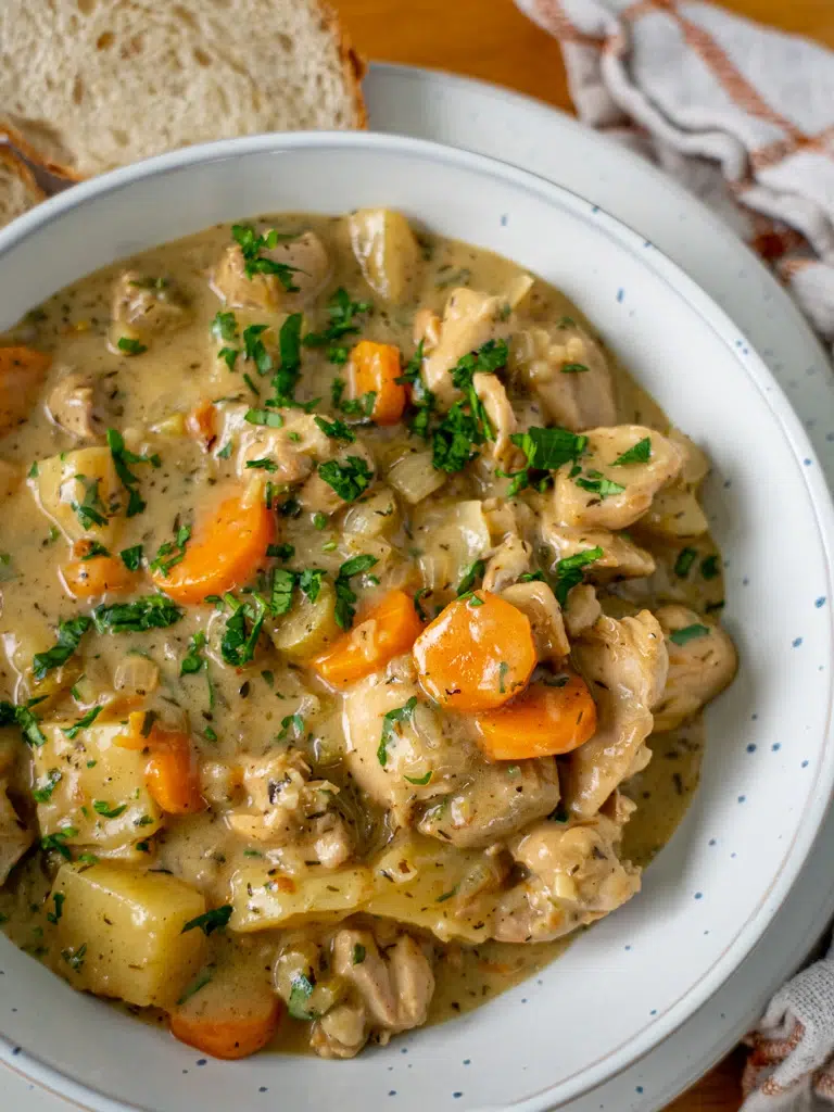 Overhead shot of a bowl of hearty chicken stew, garnished with fresh herbs.