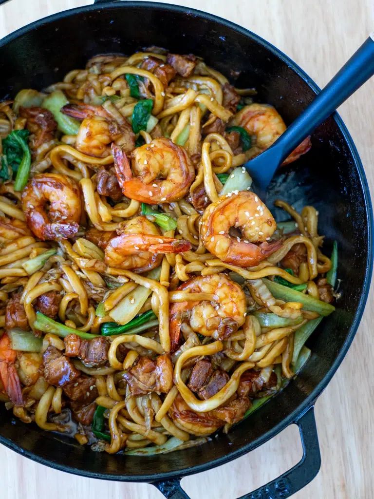 Malaysian-inspired Hokkien Mee served in a black pan with a spatula.