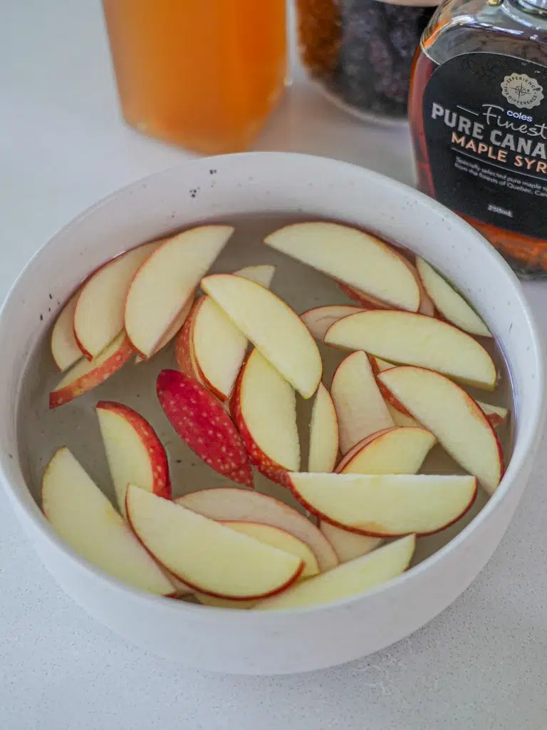 Slices of apple soaking in water in a bowl