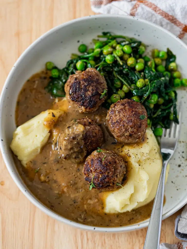Meatballs in rich, smooth gravy on a plate.