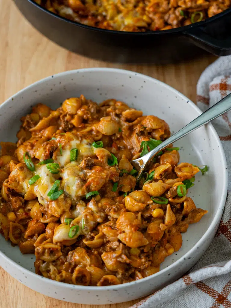 Side view of plated one-pan taco mac and cheese with a pan in the background.
